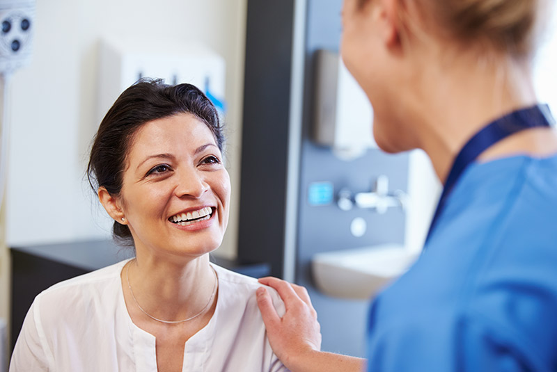 Very nice lady with dark hair smiling looking at dental assistant 